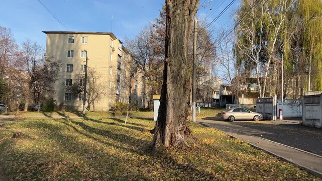 Ukraine ordinary street panning shot in Kramatorsk, Ukraine, reveals an urban housing complex and park. A lone person walks, reflecting daily life's resilience amidst the ongoing Ukraine-