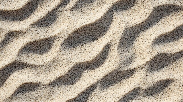 Photograph of ripples in sand with overlapping, dark shadows creating a textured pattern.