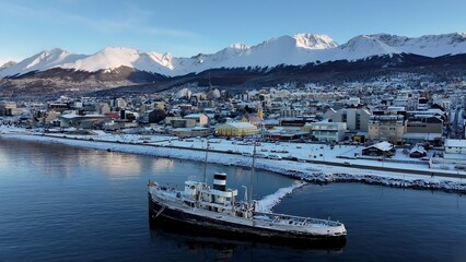 Fototapeta premium Saint Christopher Boat In Ushuaia Tierra Del Fuego Argentina. City Skyline Showing Modern And Traditional Architecture. Nature Travel Destination Snow Covered Forest Trees.