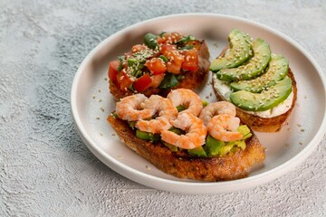 Bruschetta with avocado, shrimp, tomatoes, guacamole, cream cheese and herbs. Healthy eating.