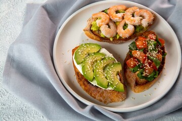 Bruschetta with avocado, shrimp, tomatoes, guacamole, cream cheese and herbs. Healthy eating.
