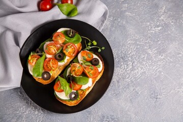 Bruschetta with cherry tomatoes, mozzarella cheese, olives and herbs. Italian Cuisine. Healthy eating.