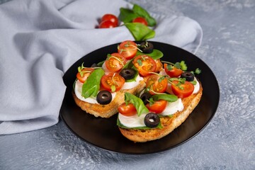 Bruschetta with cherry tomatoes, mozzarella cheese, olives and herbs. Italian Cuisine. Healthy eating.