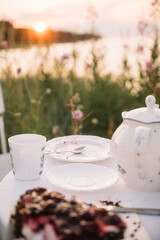 Relaxing tea time by the lakeside during sunset with dessert and floral surroundings