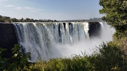 Fototapeta premium Famous Falls In Victoria Falls Matabeleland North Zimbabwe. Powerful Waterfall Cascading Over Rocky Cliff Into Mist. Recreation Falls Flowing Water Beautiful. Recreation Travel Nature.