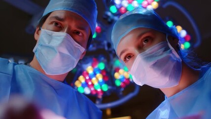 Under the surgical lights: Two medical professionals, garbed in scrubs and face masks, are immersed in a surgical setting, embodying precision and dedication in the operating room.