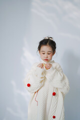 Young girl wearing a cozy white sweater.