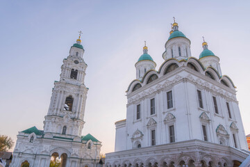 Assumption Cathedral and bell tower at Astrakhan Kremlin showcase elegant white architecture with turquoise domes and golden crosses during soft evening light, Astrakhan, Russia.
