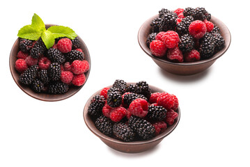 Raspberry, blackberry and mint leaf in ceramic brown bowl isolated on white
