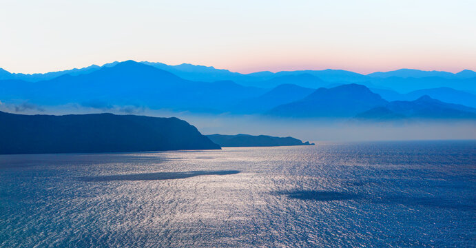 Beautiful landscape with blue misty silhouettes of mountains Blue sea in the foreground