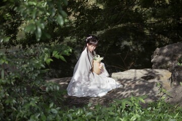 Young Asian woman in a serene natural setting with flowers.