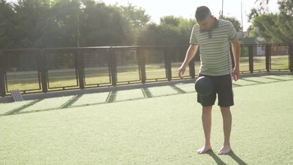 Adult man juggling soccer ball with his feet on artificial turf, showcasing his skills and passion for the sport