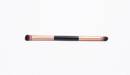 Dual-ended makeup brush with rose gold ferrules and brown bristles, used for blending eyeshadow