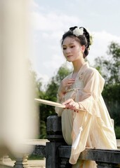Young Asian woman in traditional dress holding a fan.