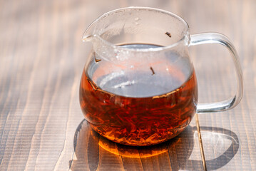 Clear Teapot with Tea Leaves and Sunlight Reflection