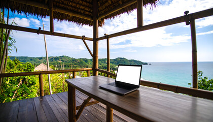 Fototapeta premium Laptop on deck overlooking tropical ocean view for remote work and vacation