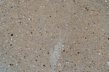 Textured concrete surface with small stones and speckles, showcasing a natural blend of colors and materials, ideal for backgrounds or design projects emphasizing industrial aesthetics