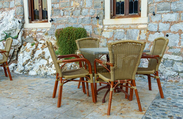 table and chairs of a cozy street cafe on the embankment against the background of a stone wall of an old building