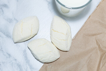 Handcrafted white cookies with a cracked texture accompanied by milk on a marble background,...