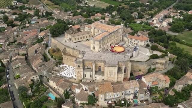 Aerial drone view of Grignan Castle surrounded by lush greenery and historic village in Provence, France &ndash; medieval fortress with scenic landscape and vibrant natural surroundings