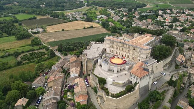 Aerial drone view of Grignan Castle surrounded by lush greenery and historic village in Provence, France &ndash; medieval fortress with scenic landscape and vibrant natural surroundings