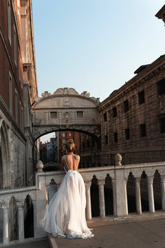 Elegant woman in a  white dress on historic stone bridge in Venice, Italy