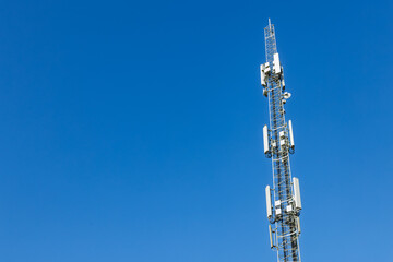 White antennas on cell tower close-up. Mobile data transmission tower with antennas against a blue clear sky, concept of telecommunications equipment, Future 6G high-speed mobile.