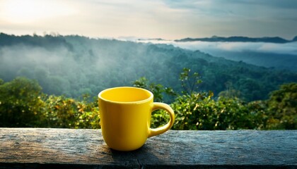 Obraz premium a bright yellow cup sits on a wooden ledge overlooking a lush green misty landscape