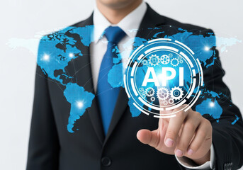  businessman touching a glowing blue api icon with a world map background, representing global technology and integration