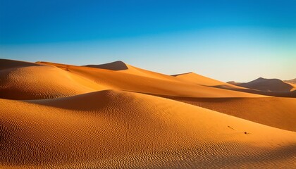 endless dunes of golden sand under clear blue sky forming abstract shapes and textures illuminated by warm glow of