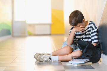 Naklejka premium Schoolboy crying in school hallway after bullying incident