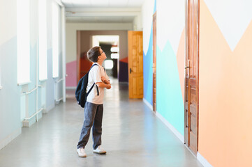 Curious pupil looking up in school hallway contemplating new school year