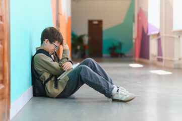 Sad schoolboy crying in school hallway after bullying incident