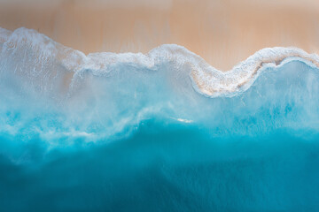 aerial view of a coastline, showcasing the harmonious interaction between the sea and the sandy beach. The composition is minimalistic yet captivating, emphasizing the natural beauty