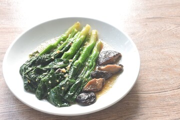 fried Kailaan Chinese kale and black mushroom dressing oyster sauce with chop garlic on plate