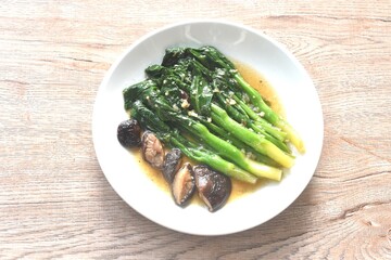 fried Kailaan Chinese kale and black mushroom dressing oyster sauce with chop garlic on plate