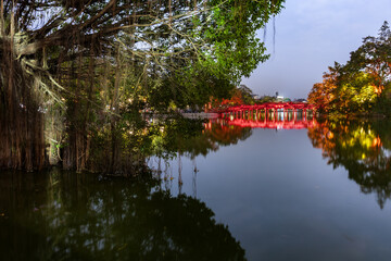  Iconic view of The Hub Bridge, a bright red wooden footbridge spanning Hoan Kiem Lake in the heart of Hanoi, Vietnam