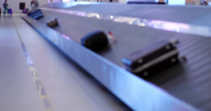 Unclaimed suitcases on move on luggage carousel, slow motion blurred view of arrivals hall at modern international airport. Concept of commonness of air travel nowadays