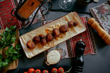 A Vibrant Culinary Presentation Featuring Savory Meatballs on a Turquoise Plate Accompanied by Fresh Vegetables and Condiments Set Against a Richly Textured Background
