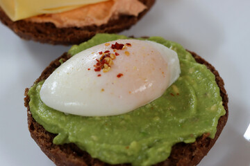 Avocado toast with poached egg and spices on a white plate