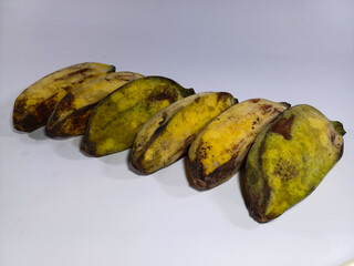 A row of bananas, showing varying stages of ripeness from green to yellow and brown, arranged on a white set. Related to healthy eating, natural food, tropical fruit, and the cycle of a fruit's life
