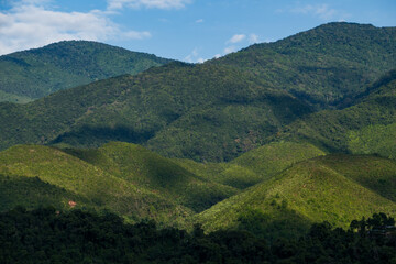 Fototapeta premium many cabin huts of a small village on the one of slope of complex mountain in sun shine and shade of clouds