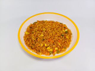 A plate of fried rice with mixed vegetables, presented on a white plate with a yellow rim. The rice is a rich, golden-brown color, well-seasoned and stir-fried. Related to Asian cuisine, cooking