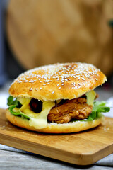 Delicious Crispy Chicken Burger with Cheese and Lettuce on a Cutting Board