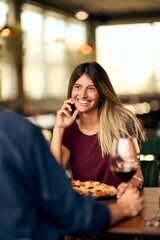 Smiling Woman Enjoying Dinner and Wine at a Cozy Restaurant Setting