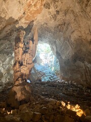 Stalagmites rising from the cave floor towards a natural skylight