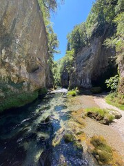 Looking up at the sky from the bottom of a canyon with a river flowing