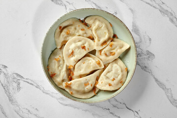 Dumplings with fried onions served on a plate on marble table