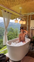 Handsome Man Relaxing in Bubble Bath on Veranda Amidst Lush Green Forest and Gentle Rain