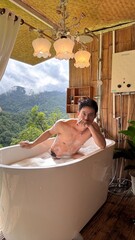 Handsome Man Relaxing in Bubble Bath on Veranda Amidst Lush Green Forest and Gentle Rain
